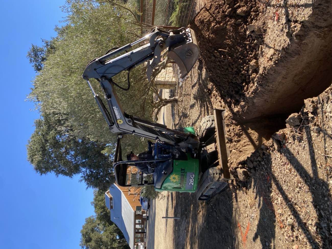 Adam Keif running a mini excavator to trench for an underground electrical line at a rural property in Paso Robles, CA